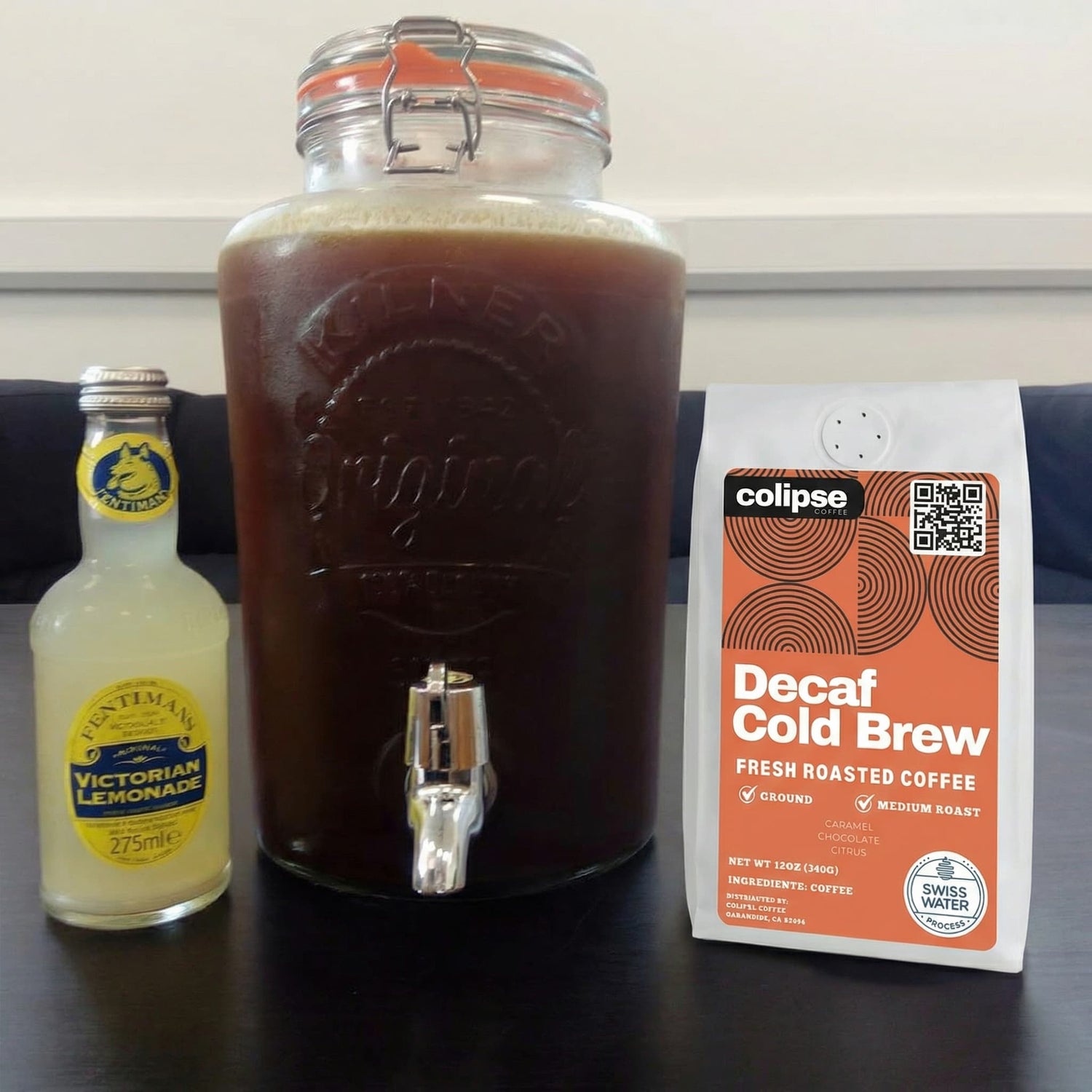 Decaf cold brew coffee with a lemonade bottle and a package of Colipse Decaf Cold Brew coffee on a table.