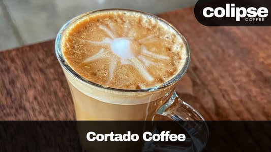 Cortado coffee in a glass mug with 'colipse Coffee' branding.