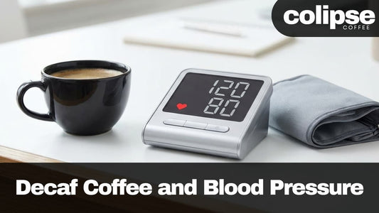 Black mug of decaf coffee next to a digital blood pressure monitor on a table with 'Colipse Coffee' branding.