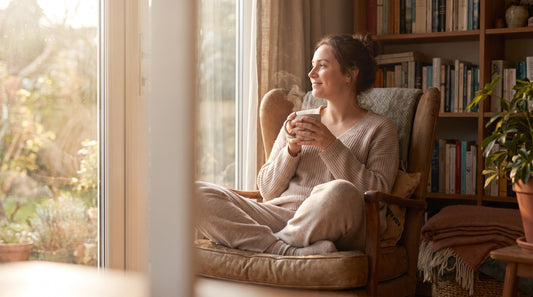 Person relaxing with mushroom coffee by a sunlit window in the morning, cortisol and stress theme