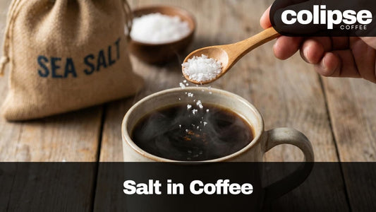 Person adding sea salt to coffee using a wooden spoon, with 'Colipse Coffee' branding.