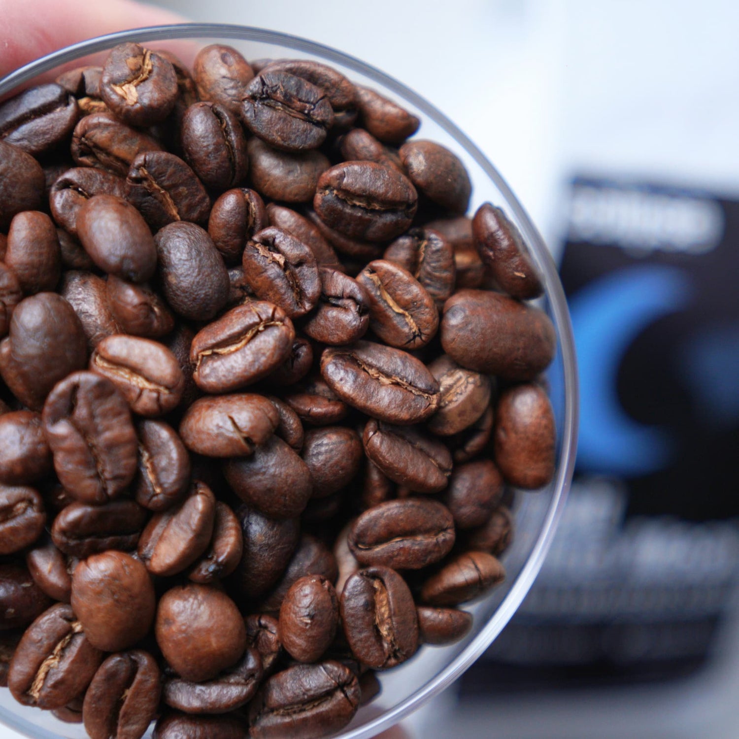 Close-up of roasted coffee beans in a clear container with a blurred background