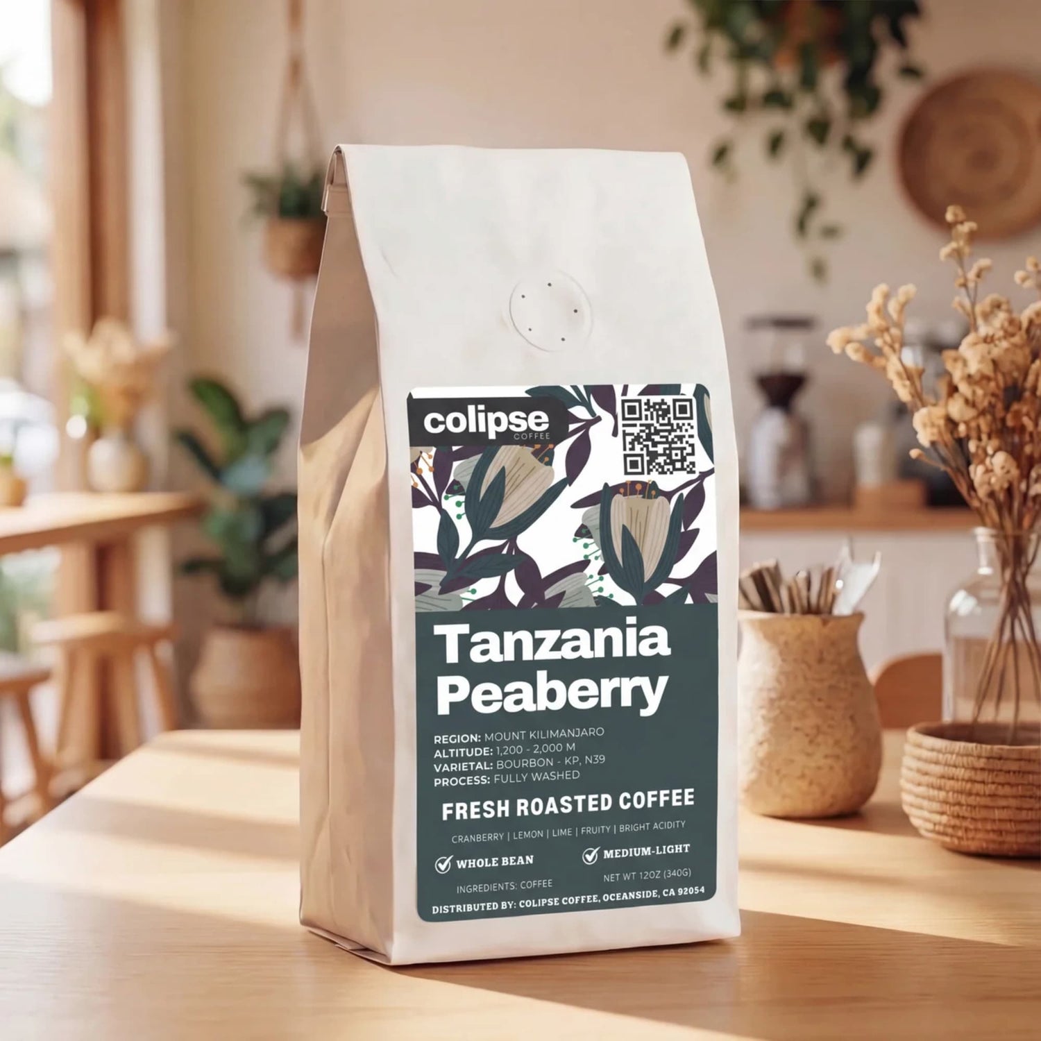 Coffee bag labeled 'Tanzania Peaberry' by Colipse on a wooden table with a homey background.