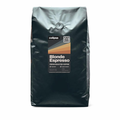 A bag of Colipse Blonde Espresso fresh roasted coffee with a graphic design depicting a sunset or sunrise scene over mountains, indicating a light roast blend with honey, citrus, and sweet berry notes.