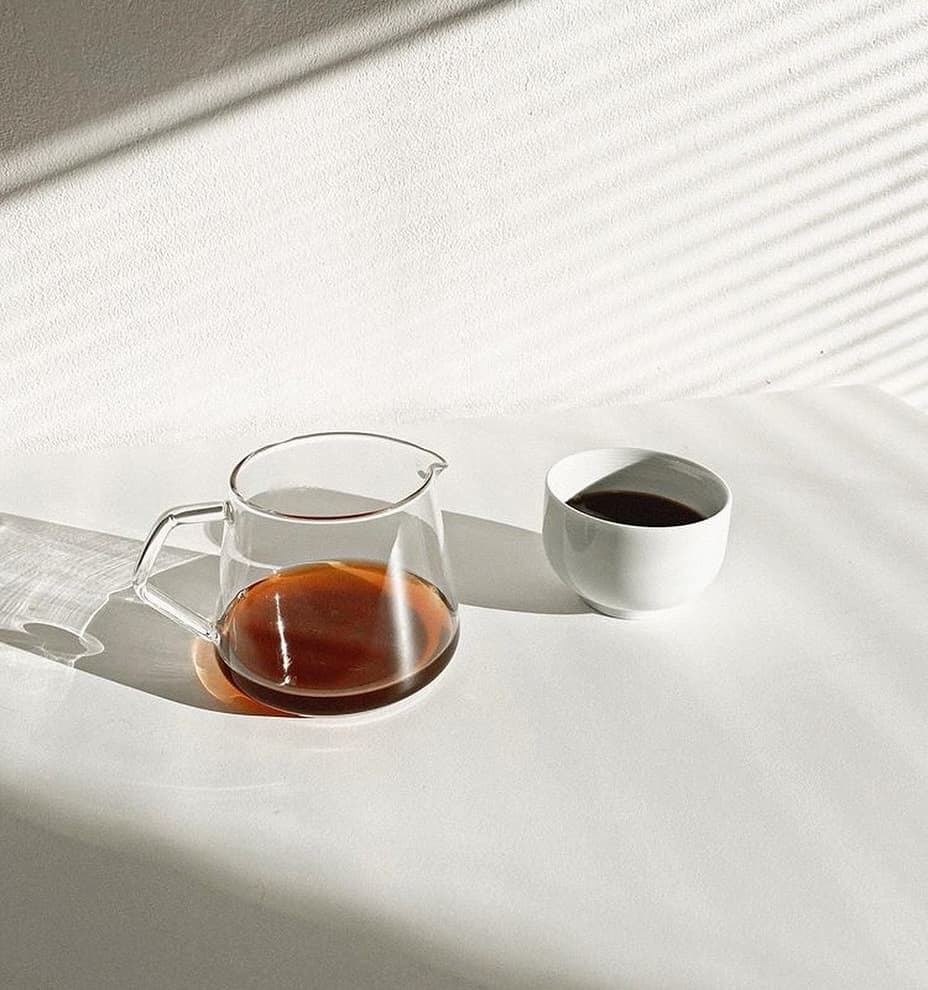 A glass carafe and small cup hold half-caff coffee in a minimalist setting