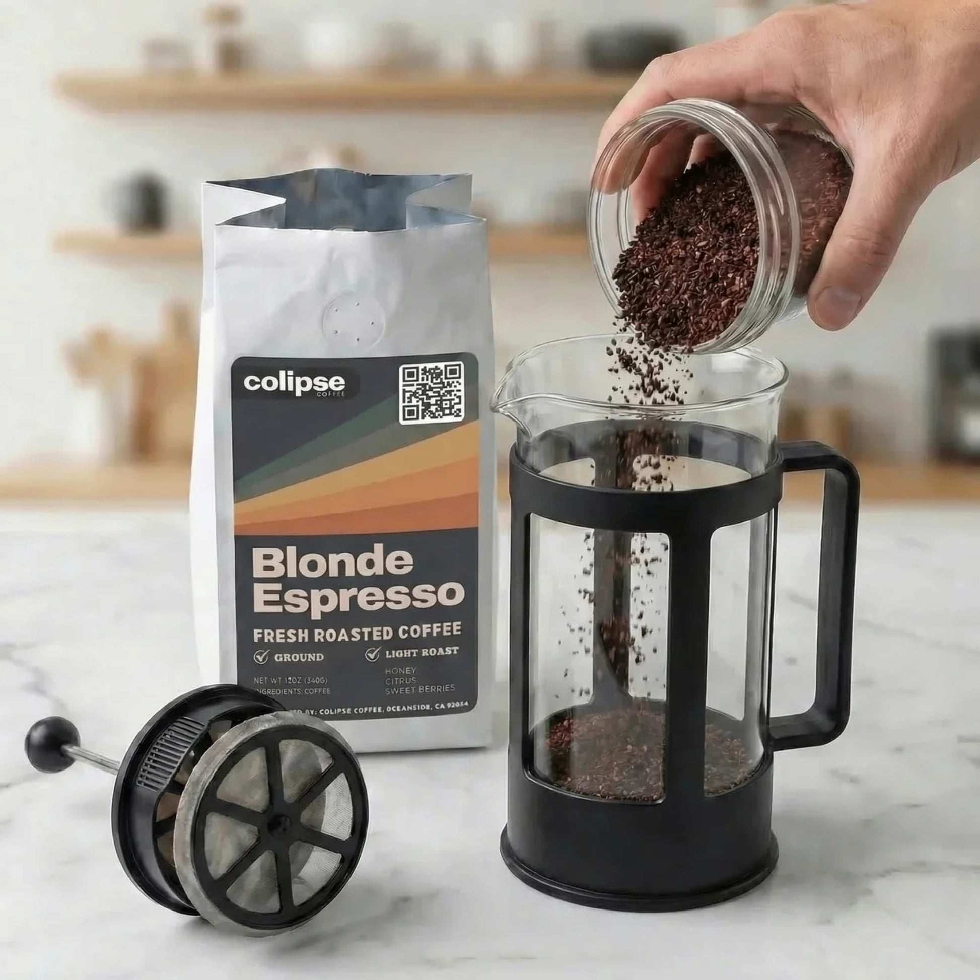 Person pouring coffee grounds into a French press with Colipse Blonde Espresso packaging in the background.