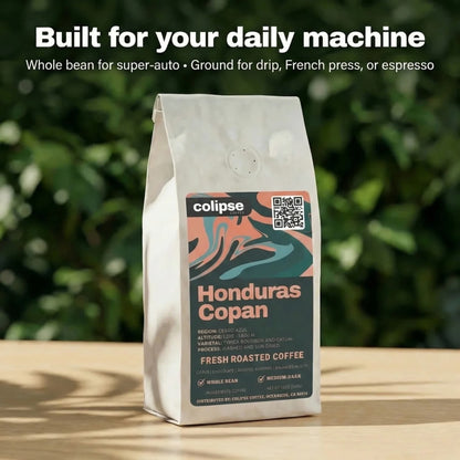 Coffee bag labeled 'Colipse Honduras Copan' on a wooden surface with a blurred green background