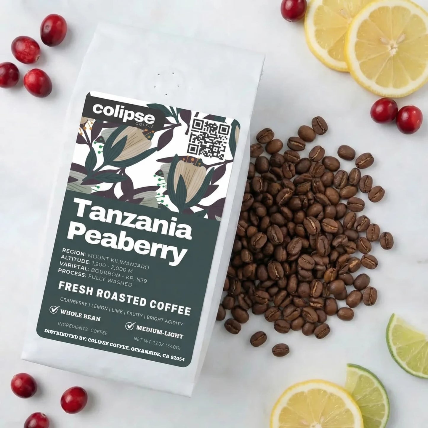 Colipse Tanzania Peaberry coffee packaging with coffee beans and fruits on a white surface