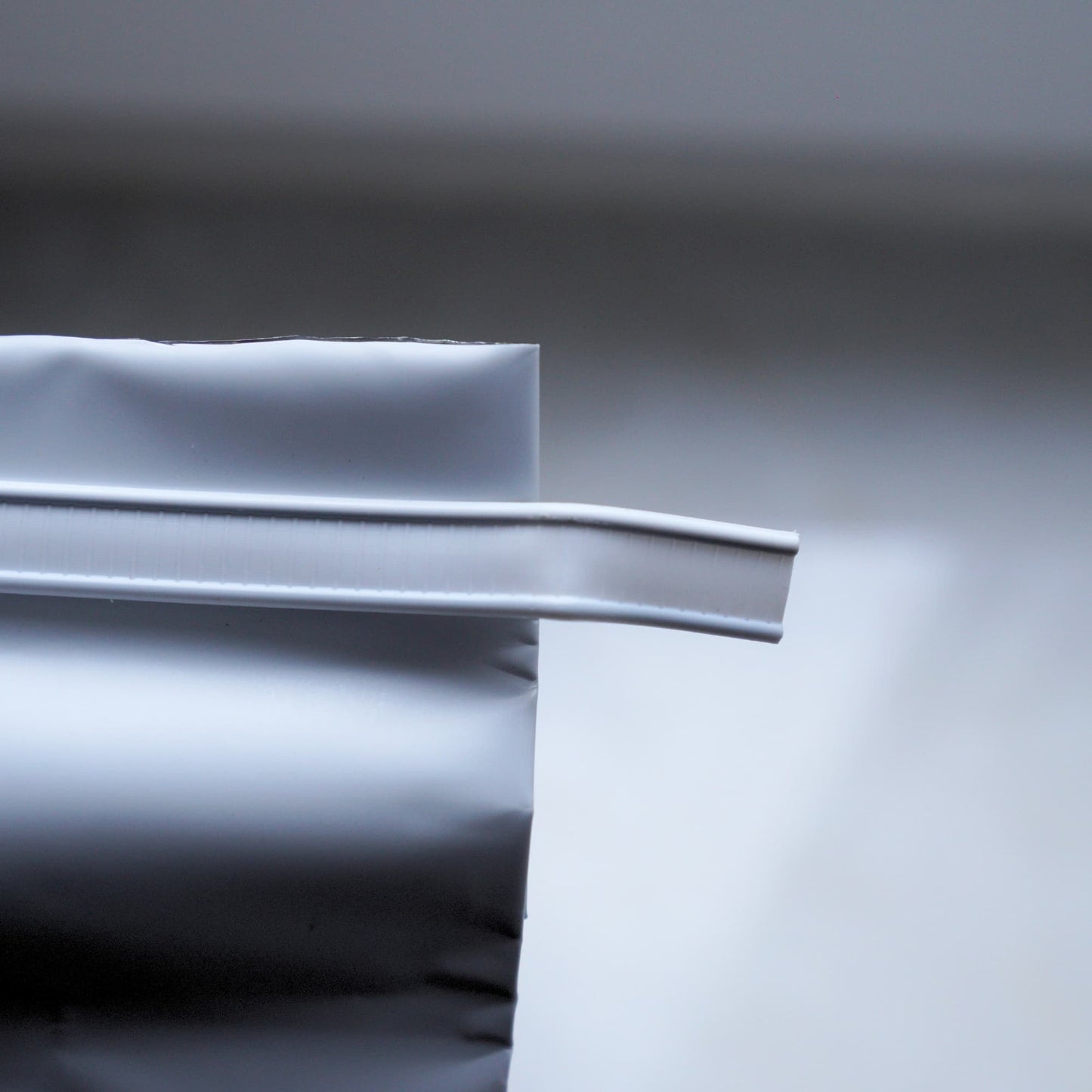 Close-up of a white plastic strip from coffee bag on a gray background