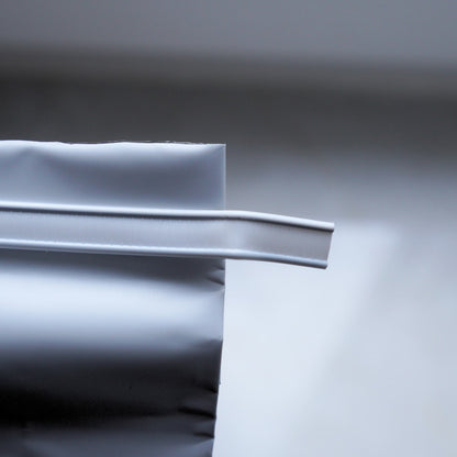 Close-up of a white plastic strip from coffee bag on a gray background