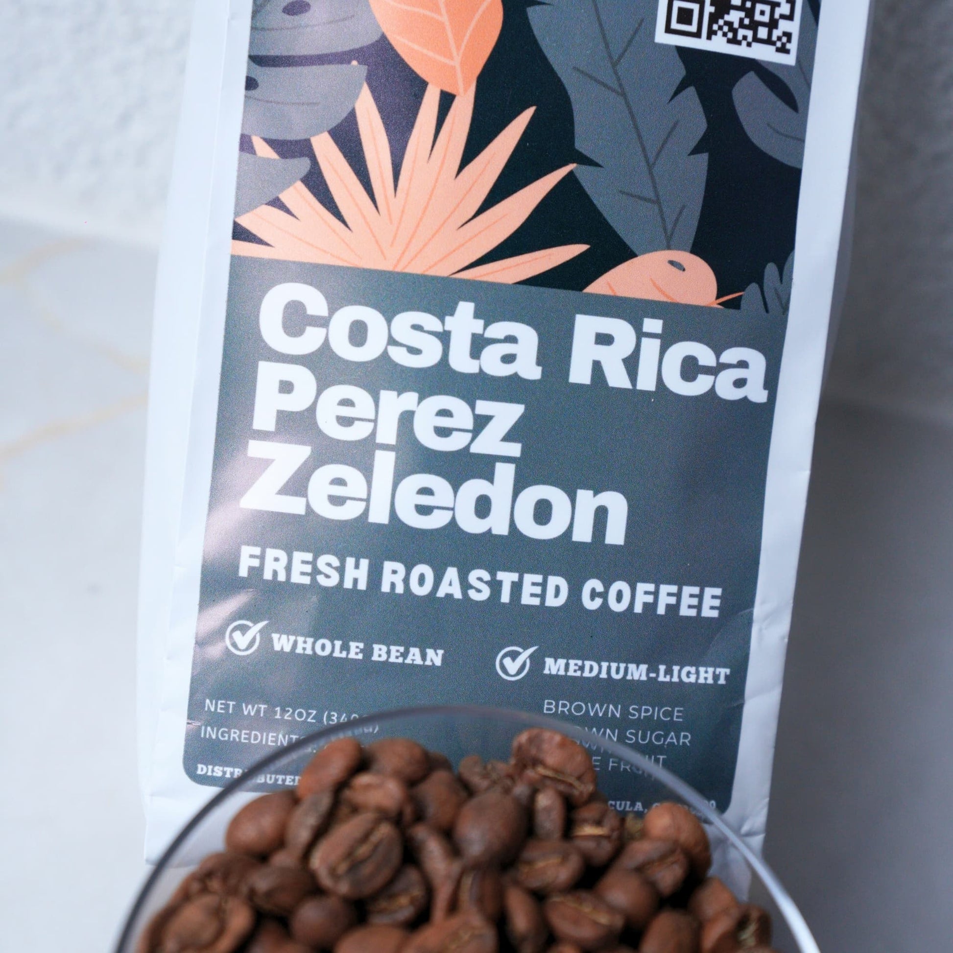 Coffee package labeled 'Costa Rica Perez Zeledon' with coffee beans in a glass bowl.