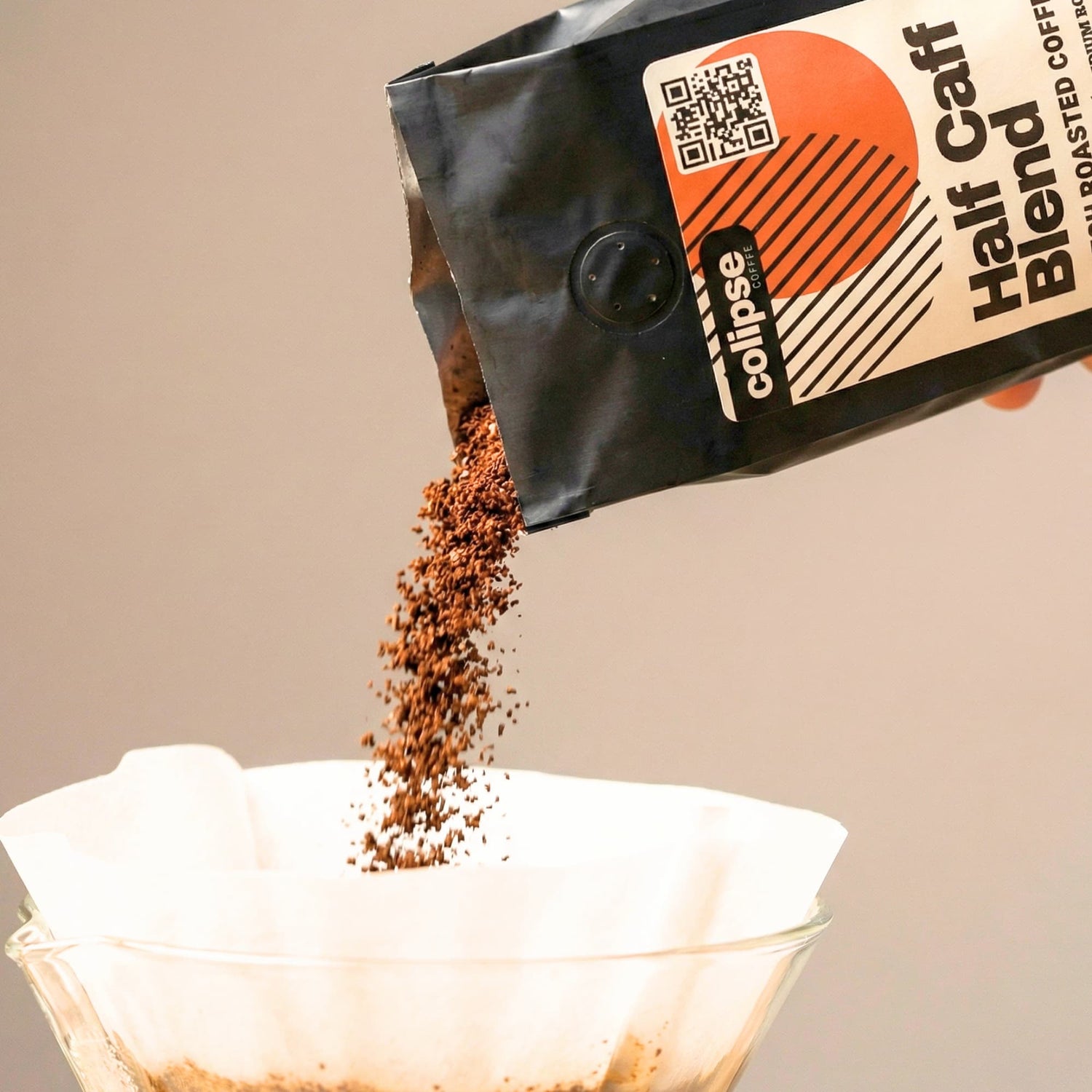 Coffee bag labeled 'Colipse Half Caff' being poured into a filter basket.