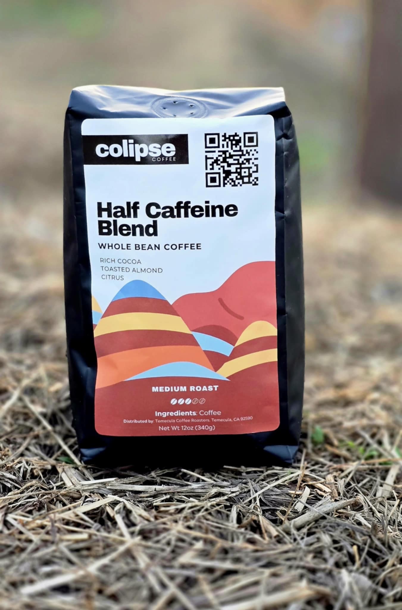 Colipse Half Caffeine Blend whole bean coffee bag displayed outdoors on dry grass.