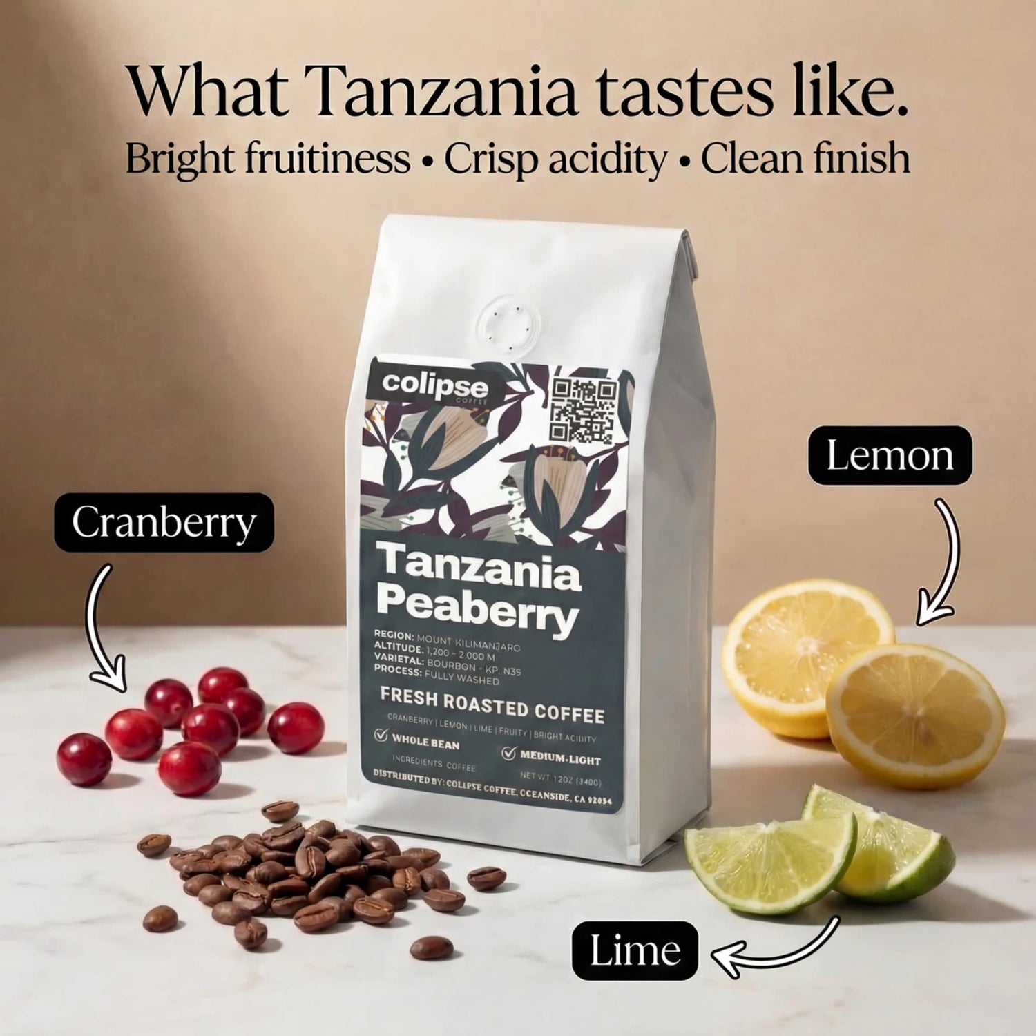 Coffee bag labeled 'Tanzania Peaberry' with coffee beans, cranberries, lemons, and lime slices on a beige background.