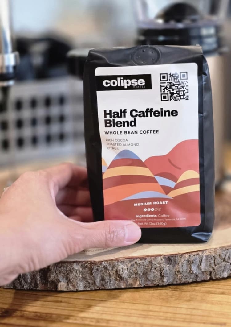 Colipse Half Caffeine Blend whole bean coffee bag displayed on a wooden surface.